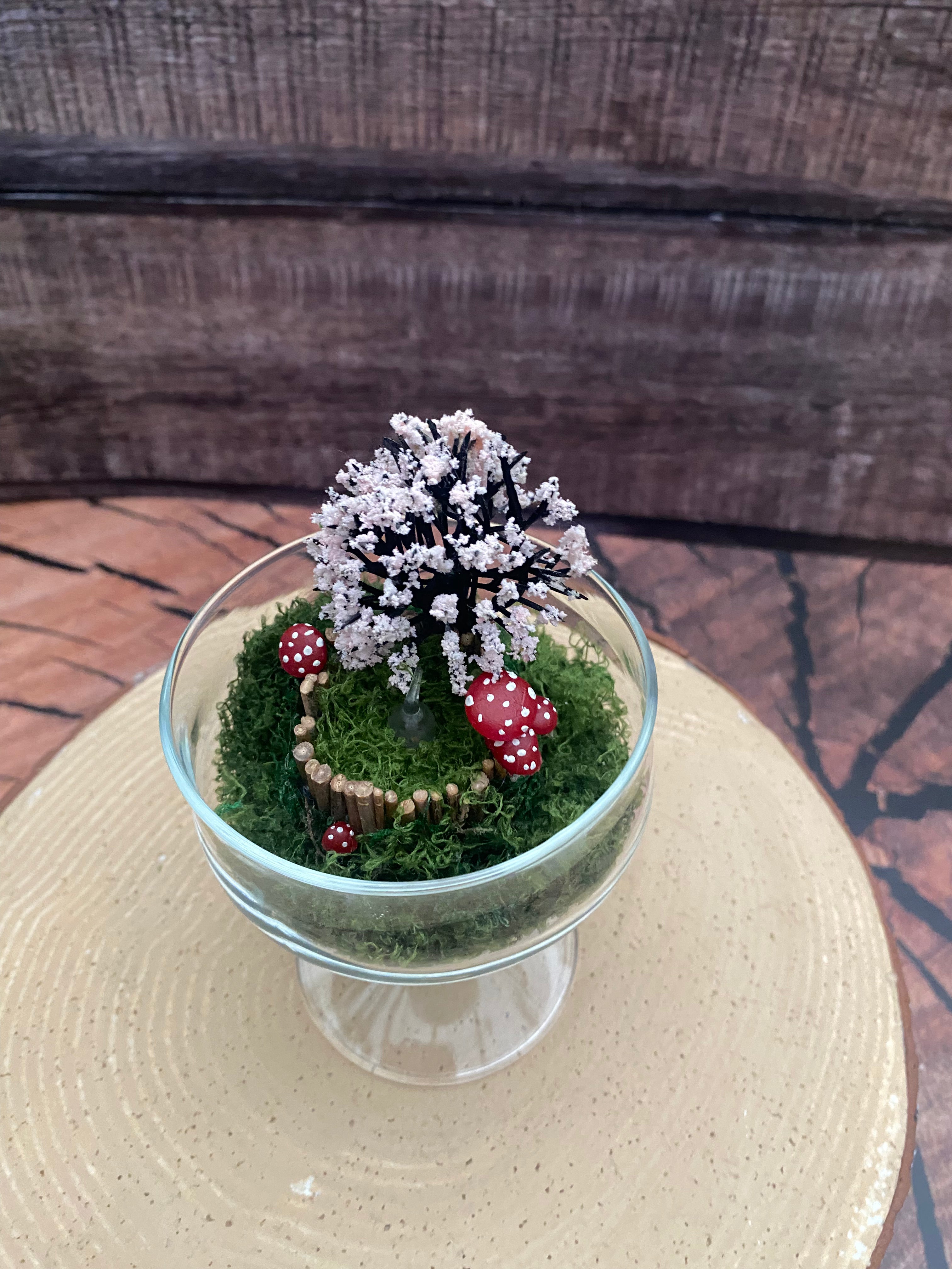 Flameless candle in mossy scene with cherry blossom tree