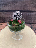 Flameless candle in mossy scene with cherry blossom tree