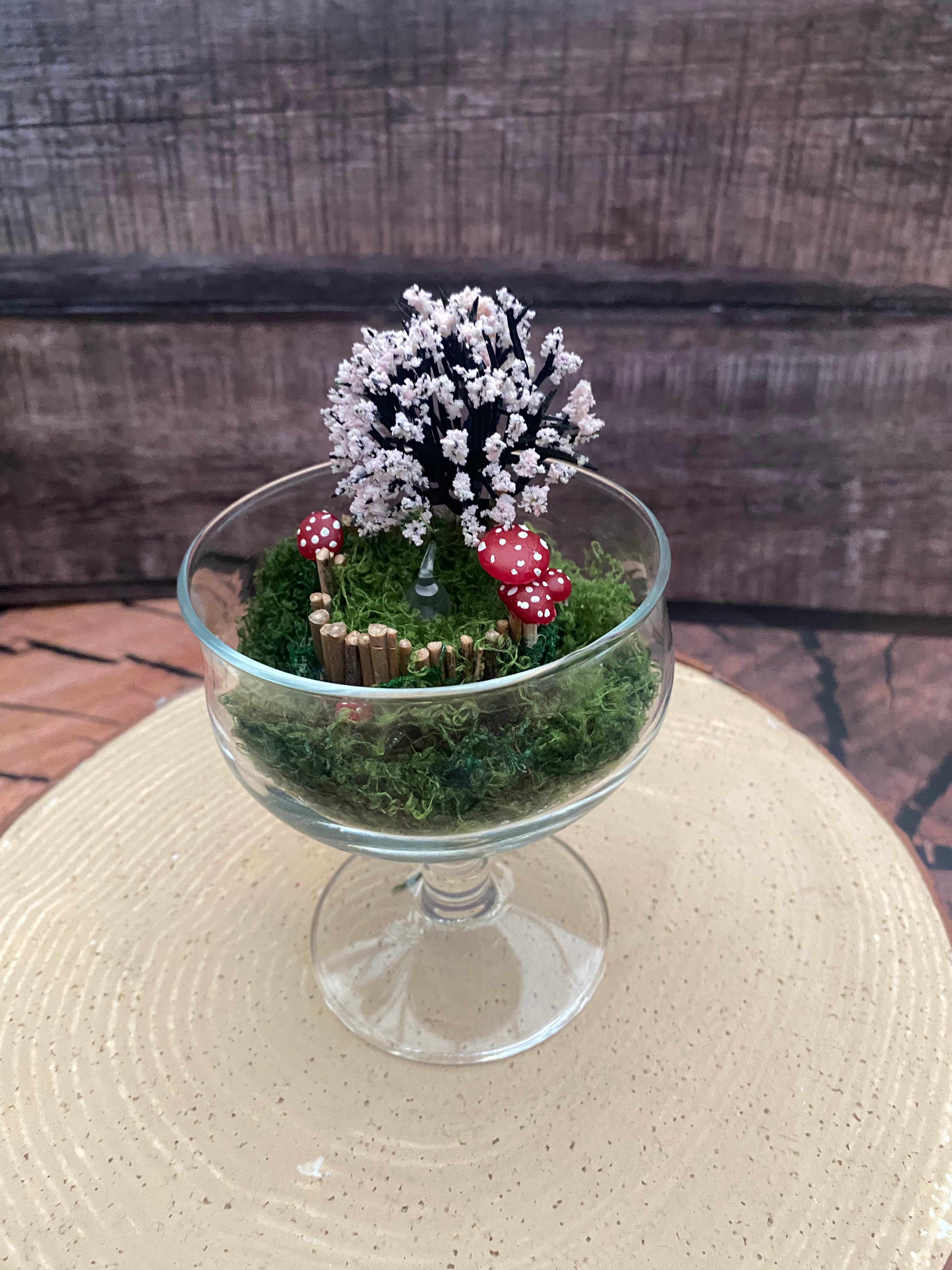 Flameless candle in mossy scene with cherry blossom tree