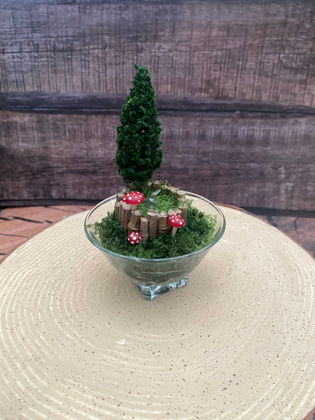 Flameless candle in small mossy campfire scene