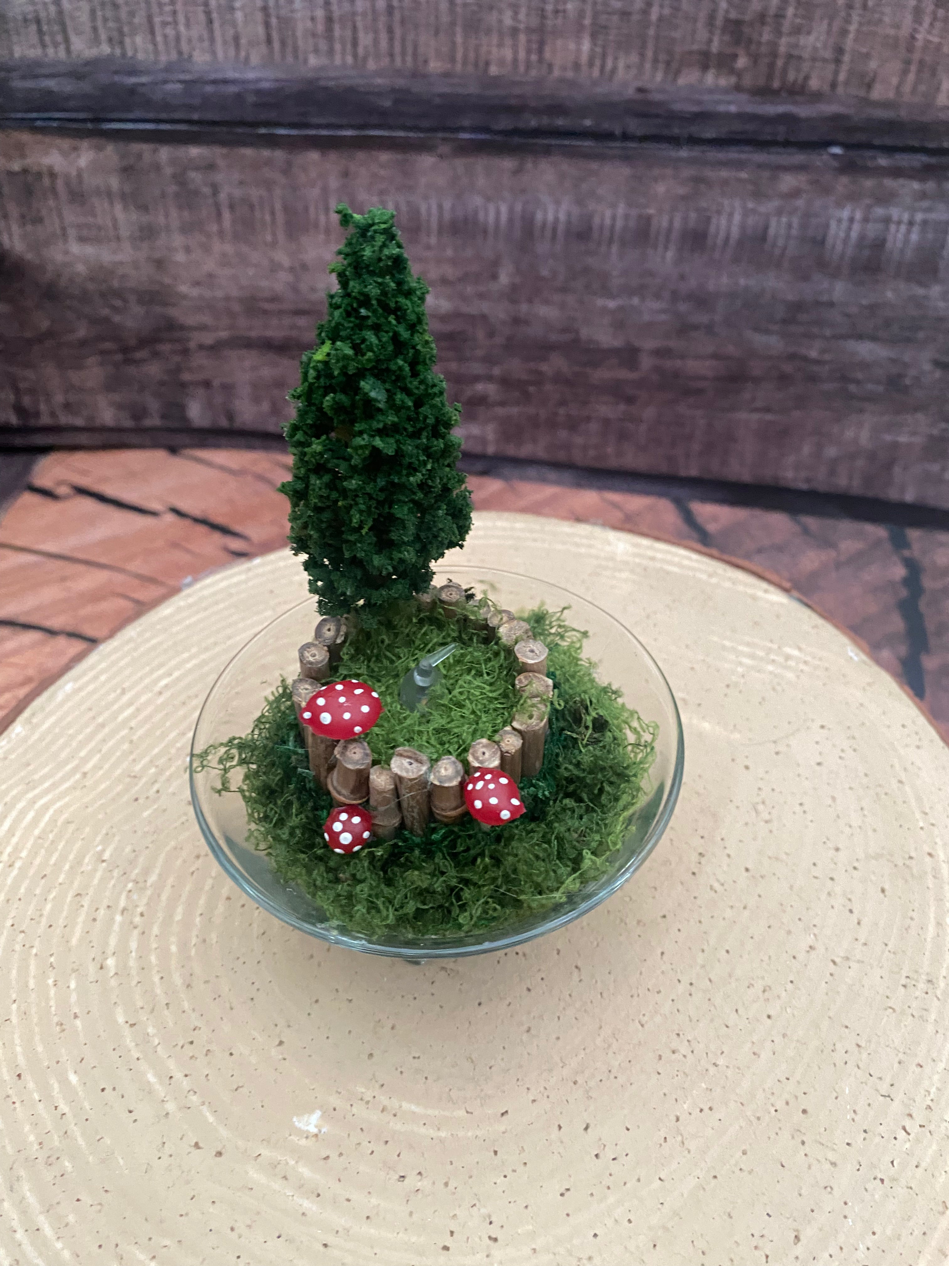 Flameless candle in small mossy campfire scene